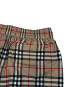 DRIPNORD Burberry monogram swim shorts in beige, black, red, and white plaid pattern. Elastic waistband.