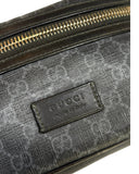 DRIPNORD Gucci GG belt bag in black and grey monogram canvas with gold zipper and leather logo patch.